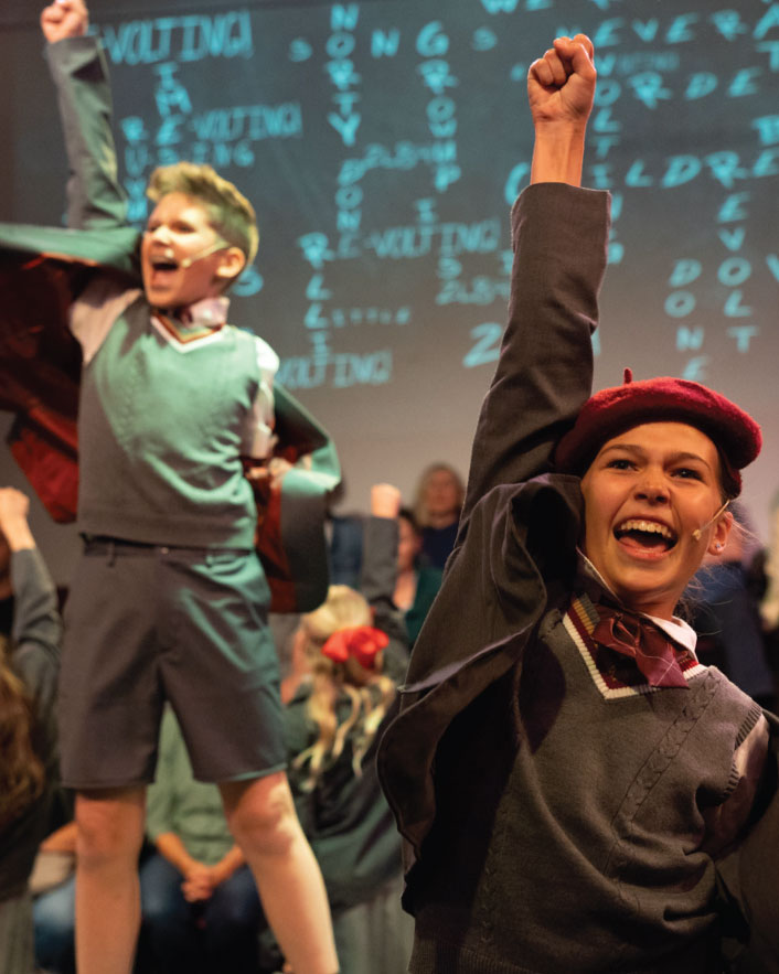 Actors on staging cheering with their arm raised at CenterStage